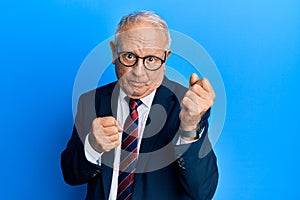 Senior caucasian man wearing business suit and tie ready to fight with fist defense gesture, angry and upset face, afraid of