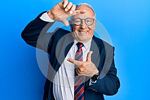 Senior caucasian man wearing business suit and tie smiling making frame with hands and fingers with happy face