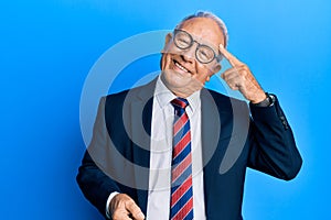 Senior caucasian man wearing business suit and tie smiling pointing to head with one finger, great idea or thought, good memory