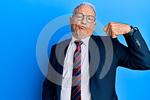 Senior caucasian man wearing business suit and tie strong person showing arm muscle, confident and proud of power