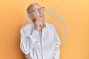 Senior caucasian man wearing casual clothes and glasses thinking concentrated about doubt with finger on chin and looking up