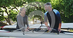 Senior caucasian man and woman preparing rowing boat for the water