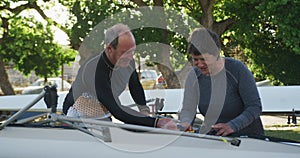 Senior caucasian man and woman preparing rowing boat for the water