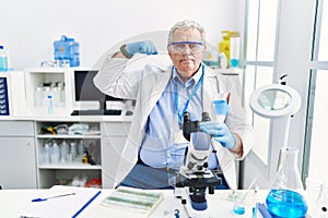 Senior caucasian man working at scientist laboratory strong person showing arm muscle, confident and proud of power