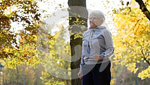 Senior caucasian pensioner woman exercising and jogging in the park in autumn. Outdoor activities. Healthy lifestyle.