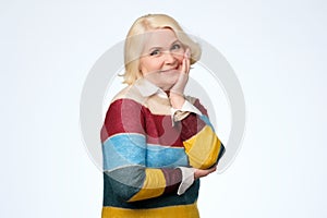 Senior caucasian woman with blonde hair in colored sweater smiling