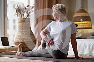 Senior caucasian woman in half spinal twist pose on mat