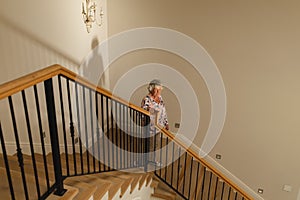 Senior caucasian woman holding handrail walking down stairs