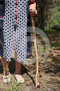 Senior Caucasian woman leans wooden walking stick, unrecognizable person