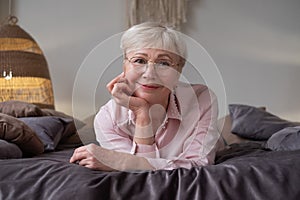 Senior caucasian woman relaxing on bed smiling at camera