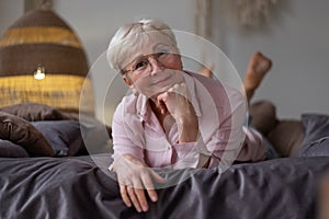 Senior caucasian woman relaxing on bed smiling at camera