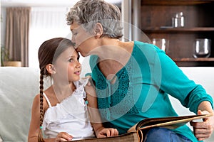 Senior Caucasian woman watching a family album at home with her granddaughter