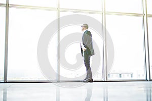 Senior cheerful businessman look at window of skycrappers in his office