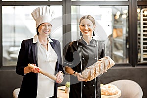 Senior chef confectioner with young assistant in the bakery shop
