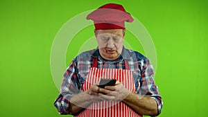 Senior chef with fingers fast texting message chatting on his smartphone.