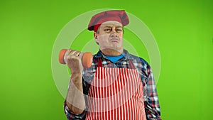 Senior chef in red apron making sports and exercising with dumbbells.