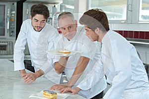 Senior chef showing cake to trainees