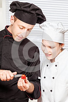 Senior chef teaches young chef to decorate fruit