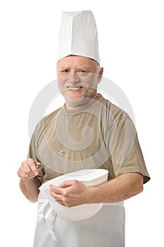 Senior chef whisking egg in kitchen