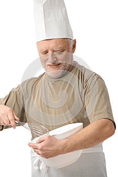 Senior chef whisking egg in kitchen