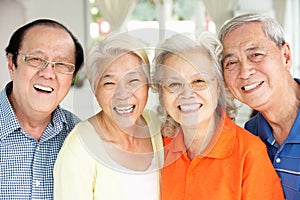 Senior Chinese Friends Relaxing On Sofa At Home