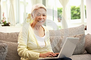 Senior Chinese Woman Using Laptop Whilst Relaxing
