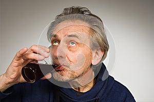 Senior citizen drinking a red wine in studio