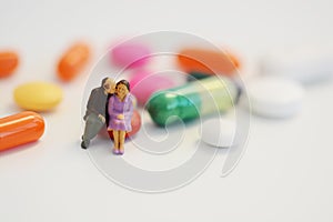 Senior citizens resting on colorful pills, social care concept