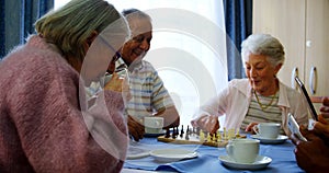 Senior citizens using mobile phone and digital tablet while playing chess 4k