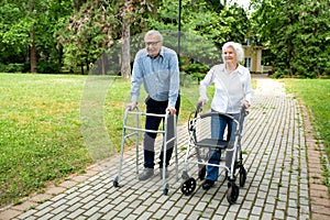 Senior citizens walking through the park with walking aid