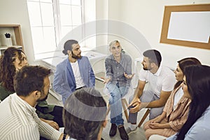 Senior coach having conversation with team of business people or company employees