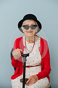 Senior, colorfully dressed woman is resting on a chair at home