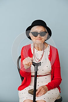 Senior, colorfully dressed woman is resting on a chair at home