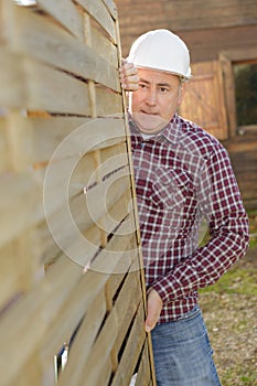 Senior construction worker carrying framed interior wall