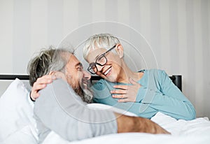 senior coule lying down in bed having fun laughing