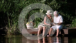 Senior couple with album outdoors.