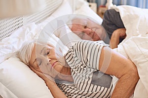 Senior couple asleep in their bed at home