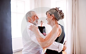 Senior couple attending dancing class in community center.