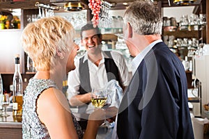 Senior couple at bar with glass of wine in hand