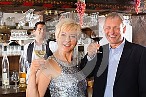 Senior couple at bar with glass of wine in hand