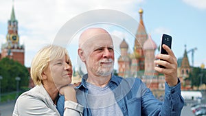 Senior couple on Basil`s Descent do selfie on mobile phone. Pensioners travel in Moscow, Russia