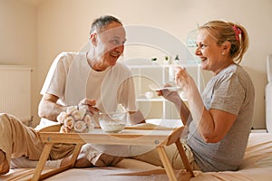 Senior couple in bed. Senior people drinking coffee in bed.