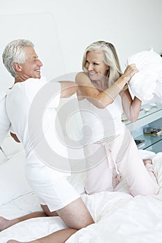 Senior Couple in bedroom having pillow fight