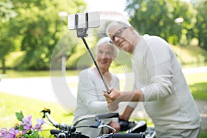 Senior couple with bicycles taking selfie at park