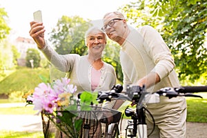 Senior couple with bicycles taking selfie at park