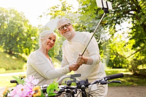 Senior couple with bicycles taking selfie at park