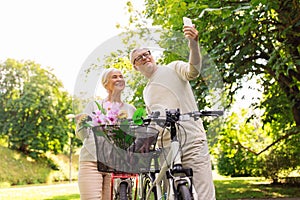 Senior couple with bicycles taking selfie at park