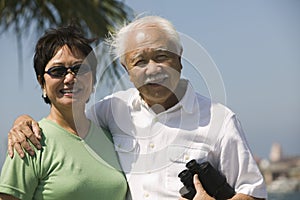 Senior couple with binoculars outdoors (portrait)