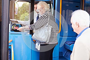 Senior Couple Boarding Bus And Using Pass