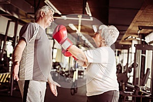 Senior couple boxing together in the gym. Senior woman with boxing glove.